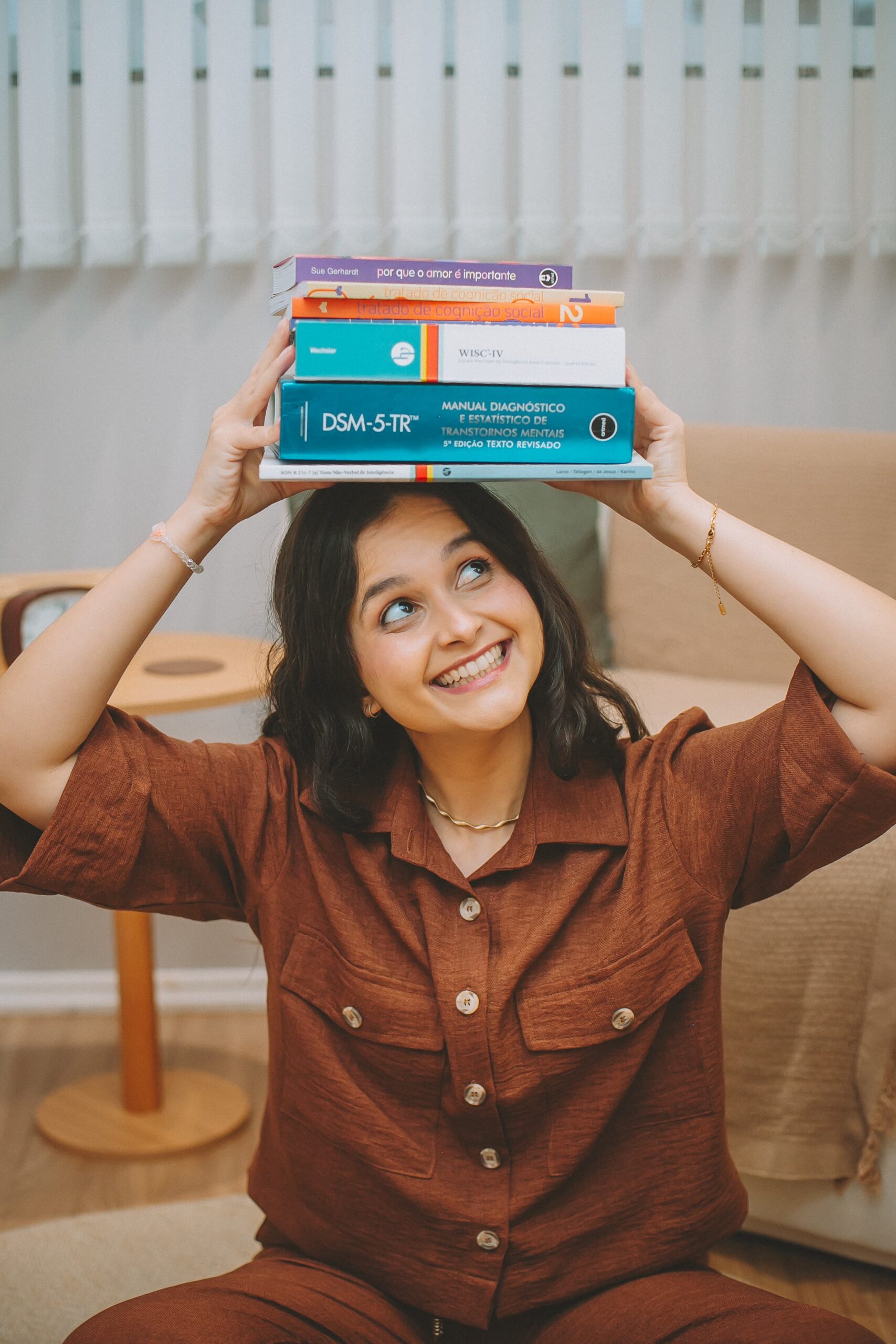 Kananda Telski segurando manuais de avaliação neuropsicológica, incluindo o DSM-5-TR
